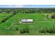 Aerial view of a metal-roofed barn on a sprawling green property with mature trees and fencing at 6805 225Th E St, Bradenton, FL 34211