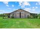 Charming barn with open doors, surrounded by green grass and mature landscaping at 6805 225Th E St, Bradenton, FL 34211