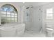 Modern bathroom with arch window, marble walls, standing shower, and a large bathtub at 6805 225Th E St, Bradenton, FL 34211