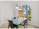 Bright dining room with a glass table, modern lighting and a large arch window offering a view of the greenery at 6805 225Th E St, Bradenton, FL 34211