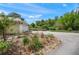 Landscaped yard with roses and a driveway, leading to a well-maintained home and garage surrounded by bamboo at 7343 Palomino Trl, Sarasota, FL 34241