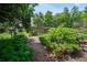 Picturesque garden space with wooden pergola, raised garden beds, mature trees, and peaceful seating areas at 7343 Palomino Trl, Sarasota, FL 34241