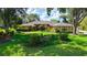 Beautifully landscaped front yard of tan single-story home with mature trees, lush lawn and manicured flower beds at 7426 Weeping Willow Blvd, Sarasota, FL 34241