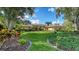 Well-manicured front yard featuring lush green grass, colorful flower beds, and mature trees framing the property at 7426 Weeping Willow Blvd, Sarasota, FL 34241