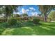 Beautifully landscaped front yard of tan single-story home with mature trees, lush lawn and manicured flower beds at 7426 Weeping Willow Blvd, Sarasota, FL 34241