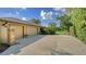 Spacious driveway leading to a two-car garage with a brick accent wall and mature landscaping at 7426 Weeping Willow Blvd, Sarasota, FL 34241