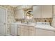 A laundry room featuring a utility sink, cabinetry, and wallpaper for a practical and visually appealing space at 7426 Weeping Willow Blvd, Sarasota, FL 34241