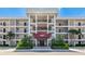 Condo building featuring a covered entrance, well-maintained landscaping and palm trees at 7461 W Country Club N Dr # 206, Sarasota, FL 34243