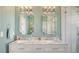 Close-up of bathroom vanity with double sinks, framed mirrors, and modern lighting fixtures against a mint-colored wall at 7915 115Th E Ave, Parrish, FL 34219