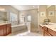 Bright bathroom featuring a soaking tub, glass-enclosed shower, and double vanity at 7915 Kavanagh Ct, Sarasota, FL 34240
