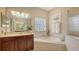 Well-lit bathroom with soaking tub, glass block window, and dual vanity at 7915 Kavanagh Ct, Sarasota, FL 34240