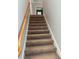 Carpeted staircase with wooden handrail leading to the upper level of the home at 10054 Crooked Creek Dr # 201, Venice, FL 34293