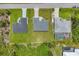 Aerial view showcasing three properties, verdant lawns and landscaping on a clear, sunny day at 10443 Riverside Rd, Port Charlotte, FL 33981