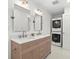 Modern bathroom with dual sinks, decorative mirrors, and a stackable washer and dryer at 1051 Indian Beach Dr, Sarasota, FL 34234