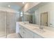 Bright bathroom features a double vanity with white cabinets and a glass-enclosed tiled shower at 11327 Burgundy Dr, Venice, FL 34293