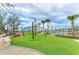 Community playground featuring modern play structures, swings, and an artificial turf surface in a lush landscaped area at 11327 Burgundy Dr, Venice, FL 34293