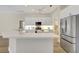 Bright open kitchen with stainless steel refrigerator, large island, white cabinets and modern appliances at 11328 Rivers Bluff Cir, Lakewood Ranch, FL 34202