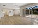 Living room with hardwood floors, white walls, and a view of the kitchen and outdoor patio through large windows at 11328 Rivers Bluff Cir, Lakewood Ranch, FL 34202