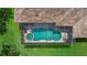 Aerial view of a private screened-in pool and spa with surrounding patio, adjacent to green lawn at 11508 30Th E Cv, Parrish, FL 34219