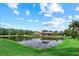 Pond view from backyard featuring a beautiful reflection and lush landscaping on a clear, sunny day at 11508 30Th E Cv, Parrish, FL 34219
