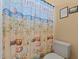 Bright bathroom featuring a toilet and a tropical beach-themed shower curtain at 11508 30Th E Cv, Parrish, FL 34219