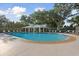 A clear view of the blue community pool, surrounded by lush trees and comfortable lounge chairs at 11508 30Th E Cv, Parrish, FL 34219