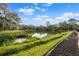 Picturesque pond surrounded by lush greenery and trees, with a walking path, offering a peaceful retreat at 11508 30Th E Cv, Parrish, FL 34219