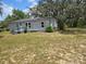 Exterior shot of the home and yard with ample space and mature trees at 13023 Taylor St, Brooksville, FL 34613