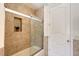 Cozy bathroom featuring a tiled shower with a glass door and a niche, next to the entry door at 13203 Lost Key Pl, Lakewood Ranch, FL 34202