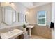 Bathroom featuring dual sinks and framed mirrors, complemented by neutral tiling and a sunny window at 13203 Lost Key Pl, Lakewood Ranch, FL 34202