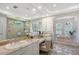 Bright bathroom featuring dual sinks, a vanity, and a luxurious soaking tub with shower; marble tiling throughout at 13203 Lost Key Pl, Lakewood Ranch, FL 34202