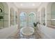 Elegant bathroom featuring a soaking tub with arched windows and shelving niches, creating a serene atmosphere at 13203 Lost Key Pl, Lakewood Ranch, FL 34202