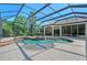 Screened-in pool features an attached spa, lush landscaping, and covered seating area at 13203 Lost Key Pl, Lakewood Ranch, FL 34202