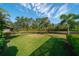 Spacious backyard features lush green lawn, mature trees, and scenic pond views and black aluminum fence at 14901 17Th E Ave, Bradenton, FL 34212