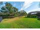 Expansive backyard with lush lawn, mature trees, and screened lanai overlooking the serene water view at 14901 17Th E Ave, Bradenton, FL 34212