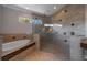 Spacious glass shower with stone surround, soaking tub, and large window letting in natural light at 14901 17Th E Ave, Bradenton, FL 34212