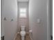 A modest water closet with a toilet, paper holder, and shelving above a small window at 14901 17Th E Ave, Bradenton, FL 34212