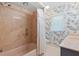 Traditional bathroom featuring a tub, marble-look surround, and a vanity with floral wallpaper at 1541 Flower Dr, Sarasota, FL 34239