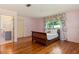 Bedroom with hardwood floors, a large window, and decorative curtains; entry into bathroom at 1541 Flower Dr, Sarasota, FL 34239