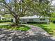 Charming single-story home with a well-maintained front yard and circular driveway shaded by a mature tree at 1541 Flower Dr, Sarasota, FL 34239