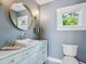 Bathroom features a round mirror above a vanity with plentiful storage, and a window providing natural light at 1732 6Th St, Sarasota, FL 34236