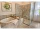 Inviting bathroom featuring soaking tub with tile surround and a glass enclosed shower with modern fixtures at 17320 Polo Trl, Bradenton, FL 34211