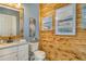 Unique bathroom with wood paneled wall, shell flamingo wall art, and granite vanity at 17320 Polo Trl, Bradenton, FL 34211