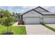Light gray home featuring a two-car garage, paved walkway and colorful landscaping, set on a green lawn at 17823 Cherished Loop, Bradenton, FL 34211