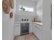 Modern bar area with white cabinetry, marble backsplash, a beverage fridge, and a window for natural light at 2124 Clematis Pl, Sarasota, FL 34239