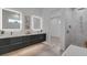 Modern bathroom boasts double vanity with sleek, illuminated mirrors, a tiled shower, and neutral tiling at 2124 Clematis Pl, Sarasota, FL 34239