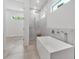 Relaxing bathroom features a soaking tub, marble-tiled walk-in shower, and neutral-toned floor tiling at 2124 Clematis Pl, Sarasota, FL 34239