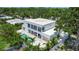 Modern, two-story home with a private pool, white facade, and a well manicured lawn surrounded by tropical trees at 2124 Clematis Pl, Sarasota, FL 34239
