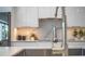 Modern kitchen with sleek white cabinets, a marble backsplash, and under-cabinet lighting at 2124 Clematis Pl, Sarasota, FL 34239