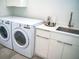 Well-equipped laundry room featuring modern washer and dryer, ample counter space, and storage cabinets at 2124 Clematis Pl, Sarasota, FL 34239